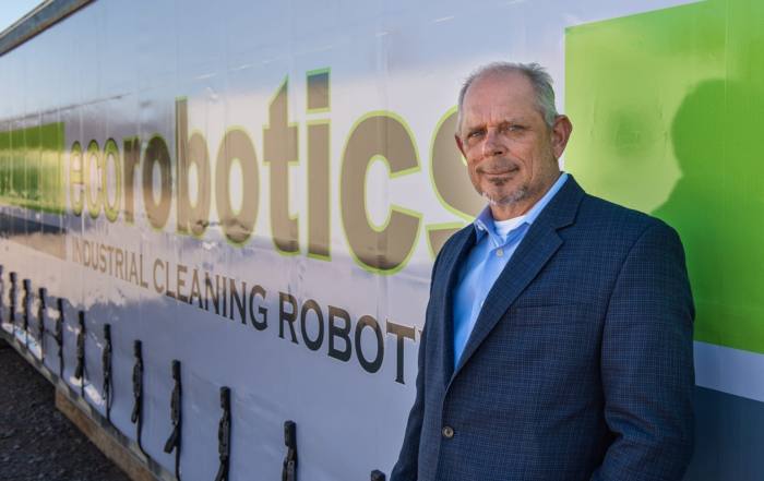 Kenny standing in front of the ecorobotics logo